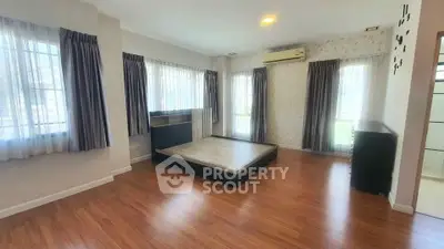 Spacious bedroom with wooden flooring and large windows for natural light