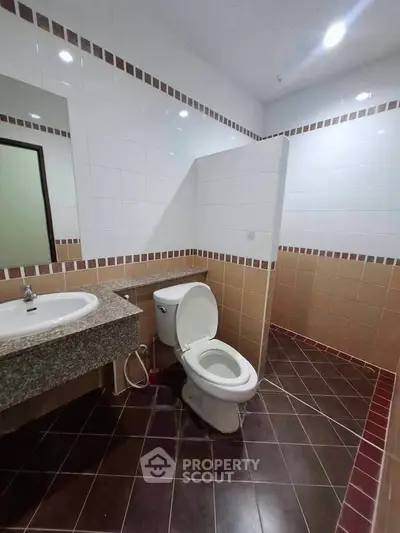 Spacious bathroom with modern fixtures and tiled walls, featuring a sleek sink and toilet.