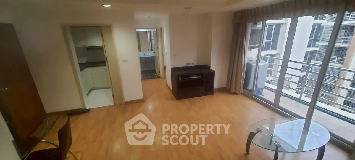 Spacious living room with wooden flooring and balcony access in modern apartment.