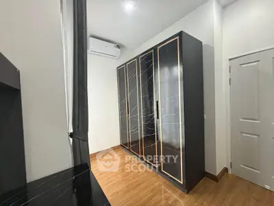Modern bedroom with sleek black wardrobe and wooden flooring