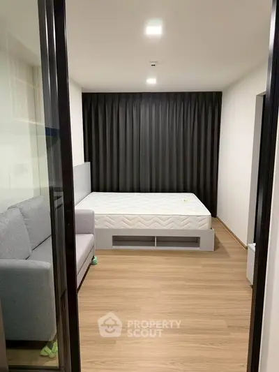 Modern bedroom with minimalist design featuring a cozy bed and sleek wooden flooring.