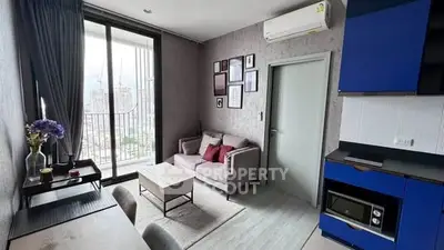 Modern living room with balcony view, stylish decor, and compact kitchen area.