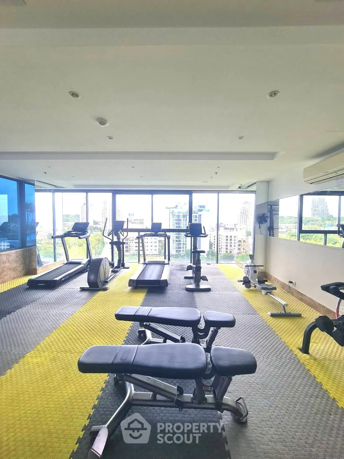 Spacious gym with modern equipment and panoramic city views, perfect for fitness enthusiasts.