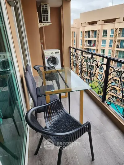 Charming balcony with pool view, featuring modern seating and a convenient washing machine setup.