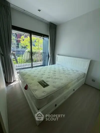 Bright bedroom with large window and garden view, featuring a comfortable bed and modern decor.