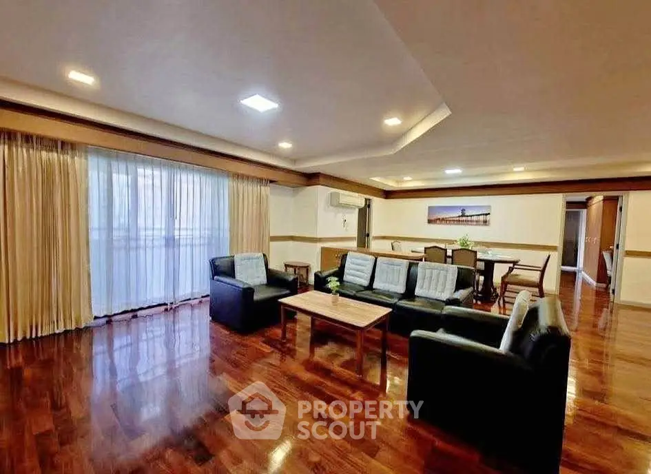 Spacious living room with elegant wooden flooring and modern furniture, perfect for family gatherings.