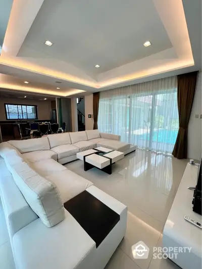 Luxurious modern living room with white sectional sofa and pool view