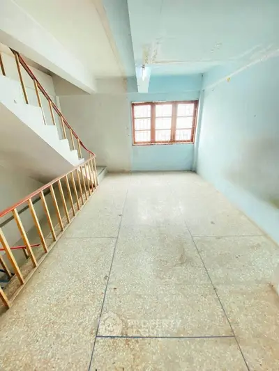 Spacious interior with natural light and staircase, ideal for renovation or creative use.