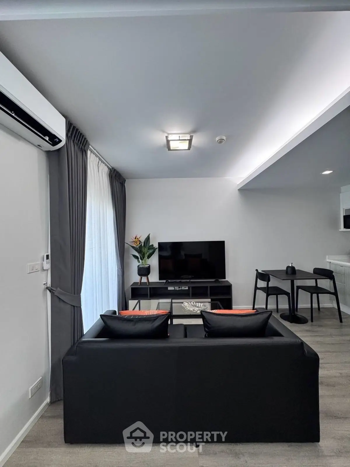 Modern living room with sleek black sofa, TV, and stylish decor in a contemporary apartment.
