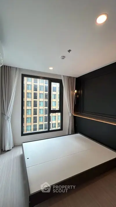 Modern bedroom with large window and stylish black accent wall in urban apartment