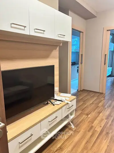 Modern apartment interior with sleek wooden flooring and stylish TV unit, showcasing a cozy and inviting living space.