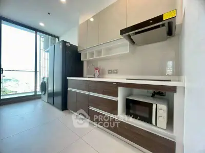 Modern kitchen with sleek cabinets, appliances, and large window view.