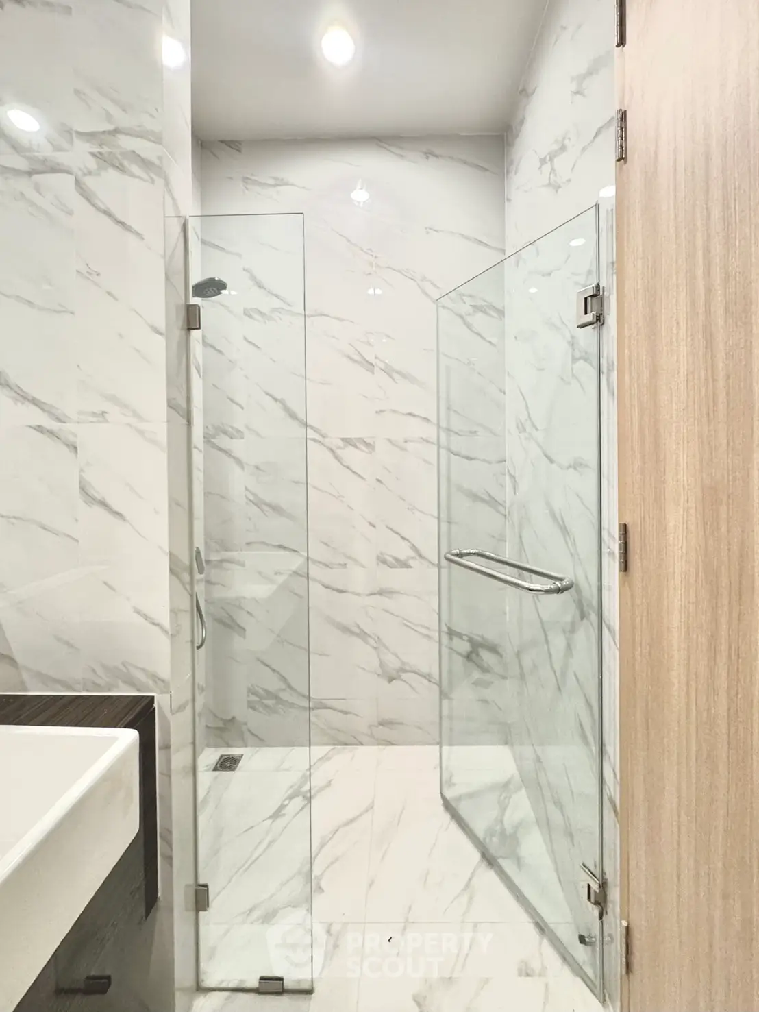 Luxurious modern bathroom with elegant marble tiles and glass shower enclosure.