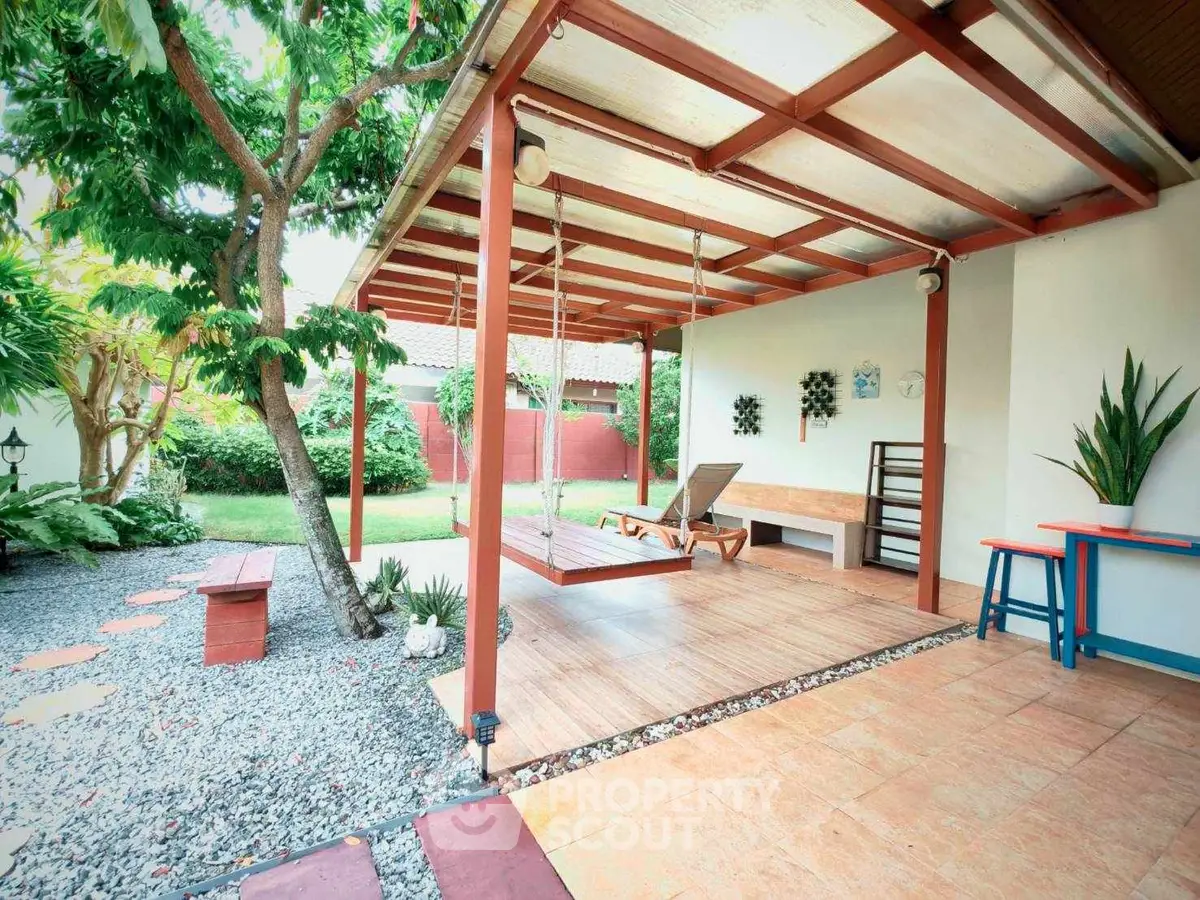 Charming garden patio with swing and lush greenery, perfect for relaxation and outdoor enjoyment.