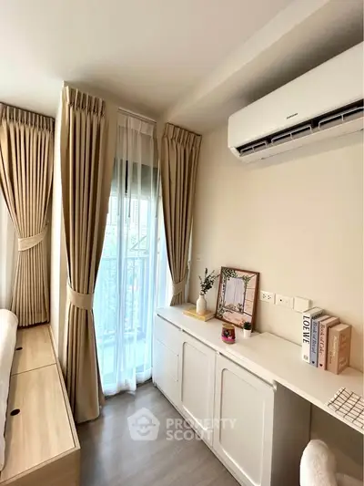 Modern bedroom with air conditioning and elegant curtains, featuring a stylish dresser and natural light.