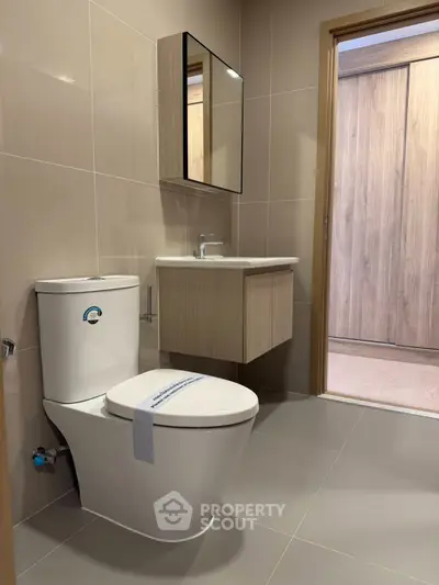 Modern bathroom with sleek fixtures and neutral tones, featuring a stylish vanity and toilet.