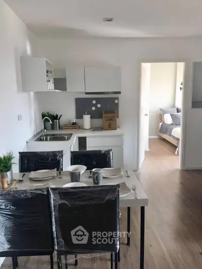 Modern open-plan kitchen and dining area with sleek design and cozy bedroom view.
