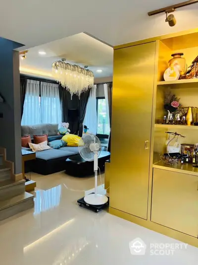 Luxurious living room with glossy floors and modern decor, featuring a plush sofa, elegant chandelier, and golden storage cabinets for a touch of opulence.