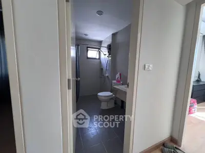 Modern bathroom with sleek design and natural light, featuring a toilet and shower area.