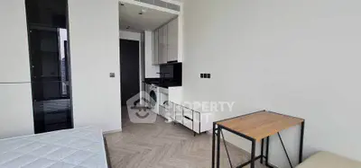 Modern studio apartment with compact kitchen and washing machine, featuring sleek design and efficient use of space.