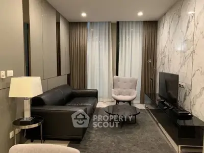 Modern living room with sleek black sofa, marble accent wall, and stylish decor