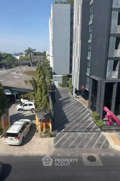 Modern urban building exterior with parking and driveway, showcasing sleek architecture and city views.
