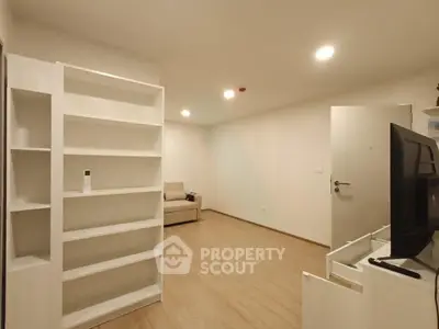 Spacious modern living room with built-in shelving and sleek wooden flooring.