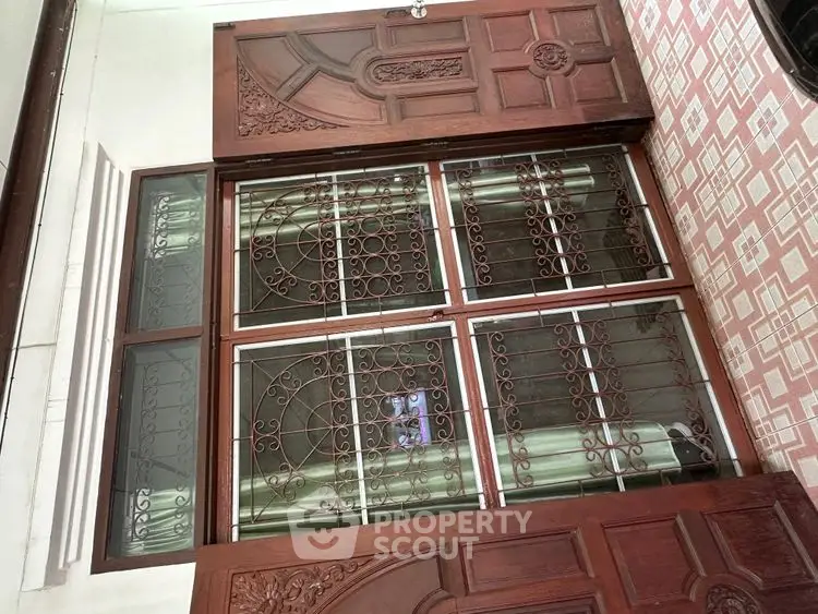 Elegant wooden entrance with intricate ironwork and tiled flooring