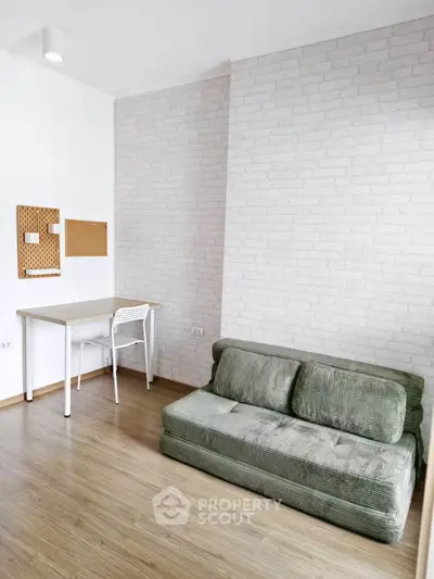 Modern minimalist living room with green sofa and study desk, featuring white brick accent wall.