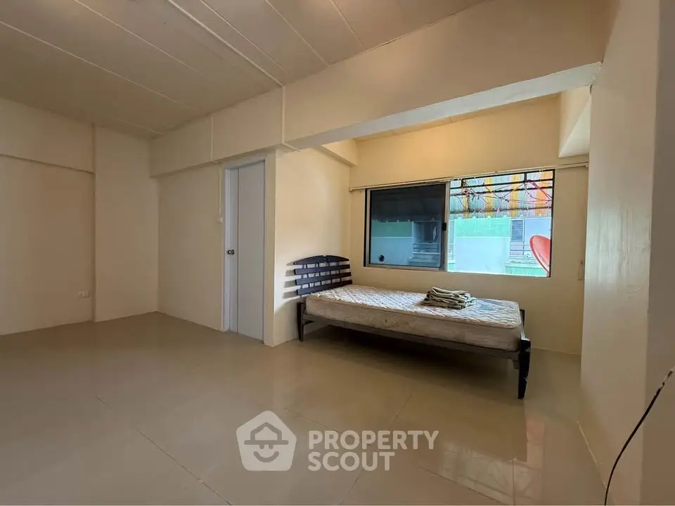 Spacious bedroom with minimalist design and large window for natural light.