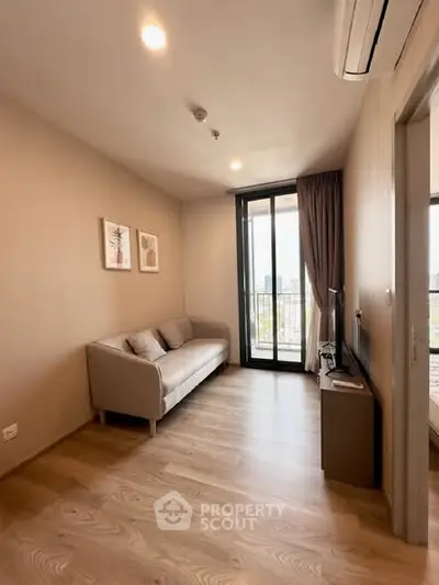Modern living room with balcony view, featuring sleek wooden flooring and stylish decor.