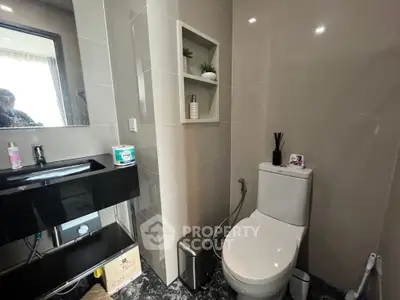 Modern bathroom with sleek fixtures and built-in shelving, featuring a stylish black sink and contemporary decor.