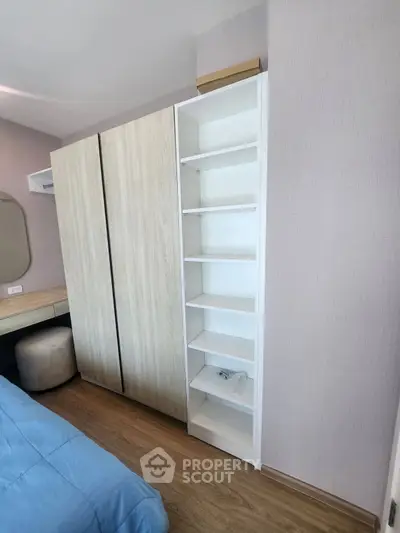 Modern bedroom with built-in wardrobe and shelving, featuring stylish wood flooring and cozy decor.