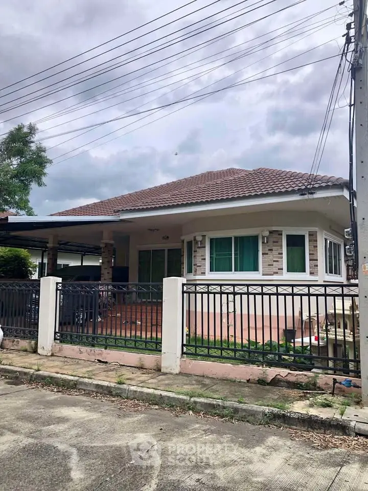 Charming single-story house with tiled roof and gated front yard in a serene neighborhood.
