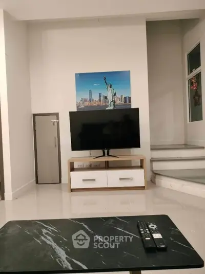 Modern living room with TV and stylish decor, featuring a Statue of Liberty artwork.