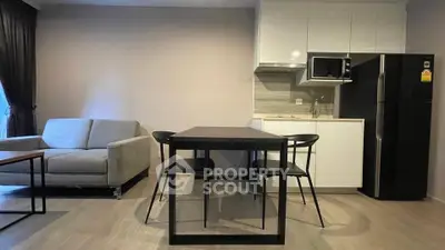 Modern open-plan living room with sleek kitchen and dining area, featuring contemporary furniture and appliances.