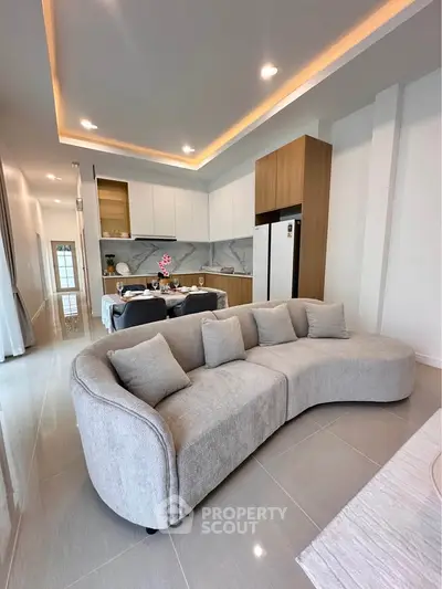 Modern open-plan living room with stylish kitchen and cozy curved sofa