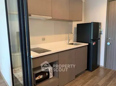 Modern compact kitchen with sleek cabinetry and built-in appliances in a stylish apartment.