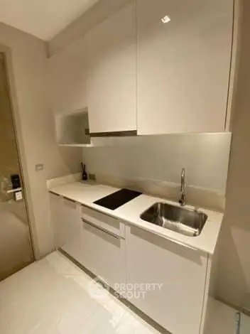 Modern compact kitchen with sleek white cabinets and integrated appliances