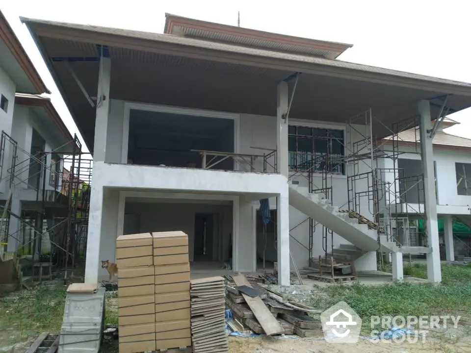 Modern two-story house under construction with scaffolding and building materials