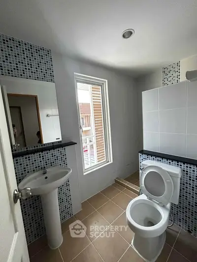 Modern bathroom with sleek fixtures and natural light from window.