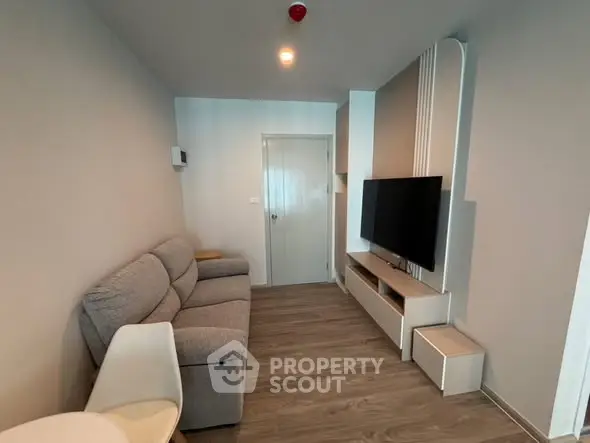 Modern living room with sleek furniture and mounted TV in a cozy apartment.