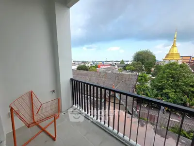 Charming balcony with city view and unique orange chair, perfect for relaxation.