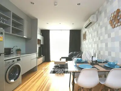 Modern living room with open kitchen, featuring stylish decor and natural light.