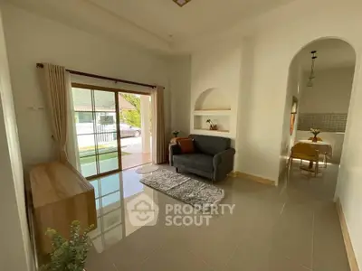 Charming living room with modern decor and natural light, featuring a cozy sofa and elegant dining area.
