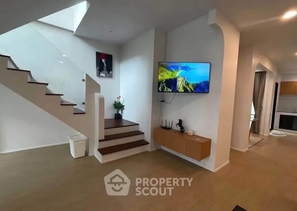 Modern living room with staircase and wall-mounted TV in stylish home interior.