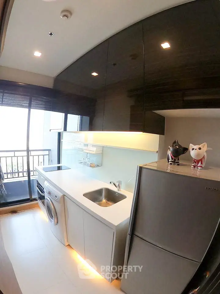 Modern kitchen with sleek cabinets, stainless steel appliances, and balcony view.
