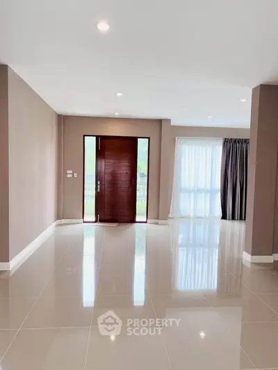 Spacious modern living room with glossy tiled floors and large windows for natural light.