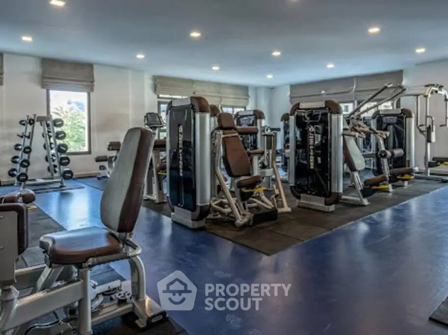 Spacious modern gym with state-of-the-art equipment and natural lighting in luxury real estate property.