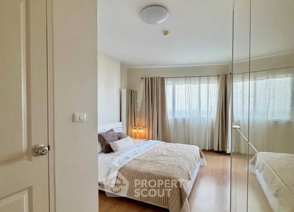 Spacious bedroom with large windows and elegant decor in modern apartment.